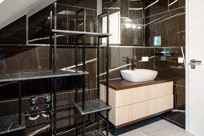 Une salle de bain moderne avec un meuble-lavabo en marbre, une étagère en verre et un lavabo blanc.