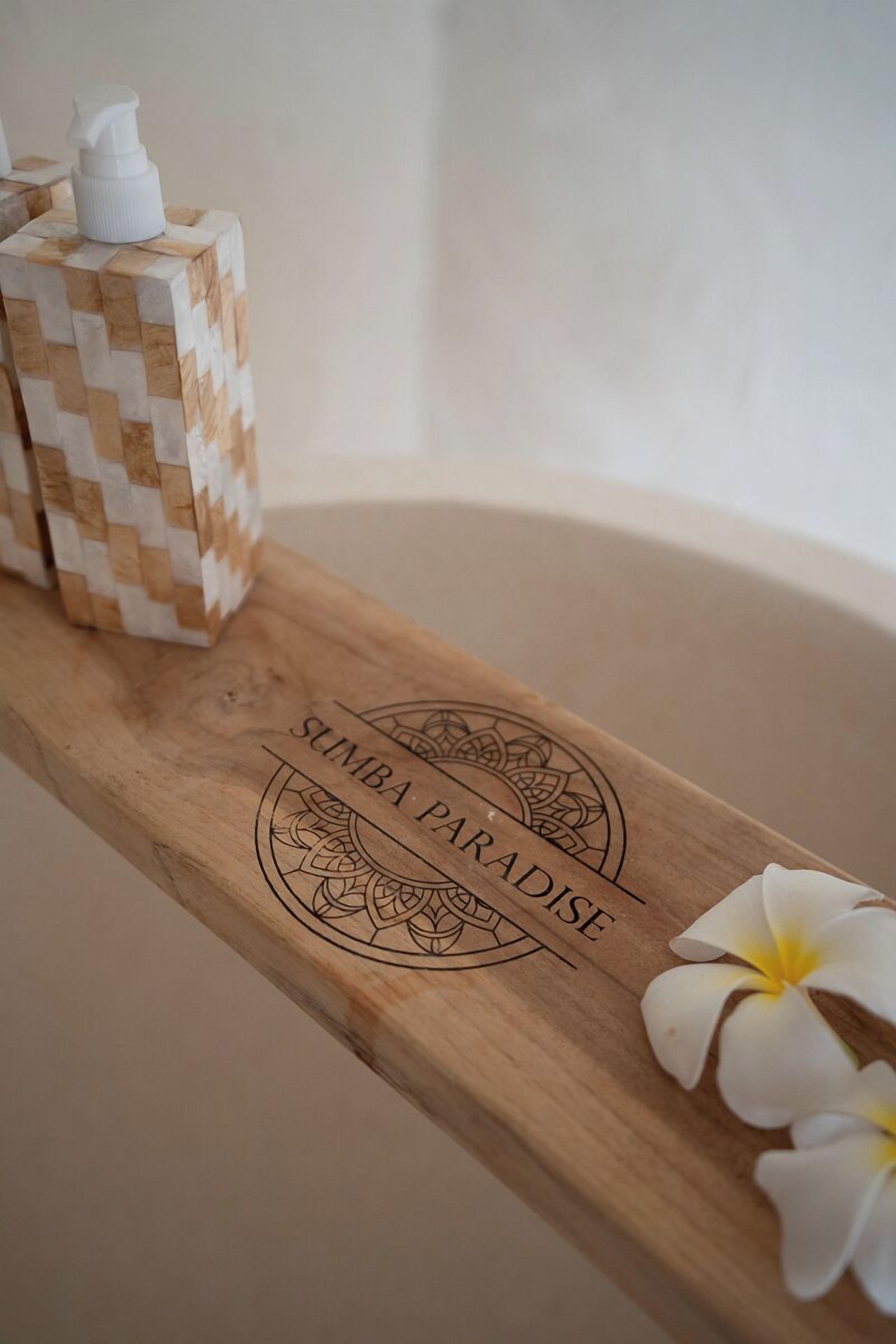 Un vassoio di legno con un emblema decorativo e del testo, una bottiglia bianca e un fiore bianco.