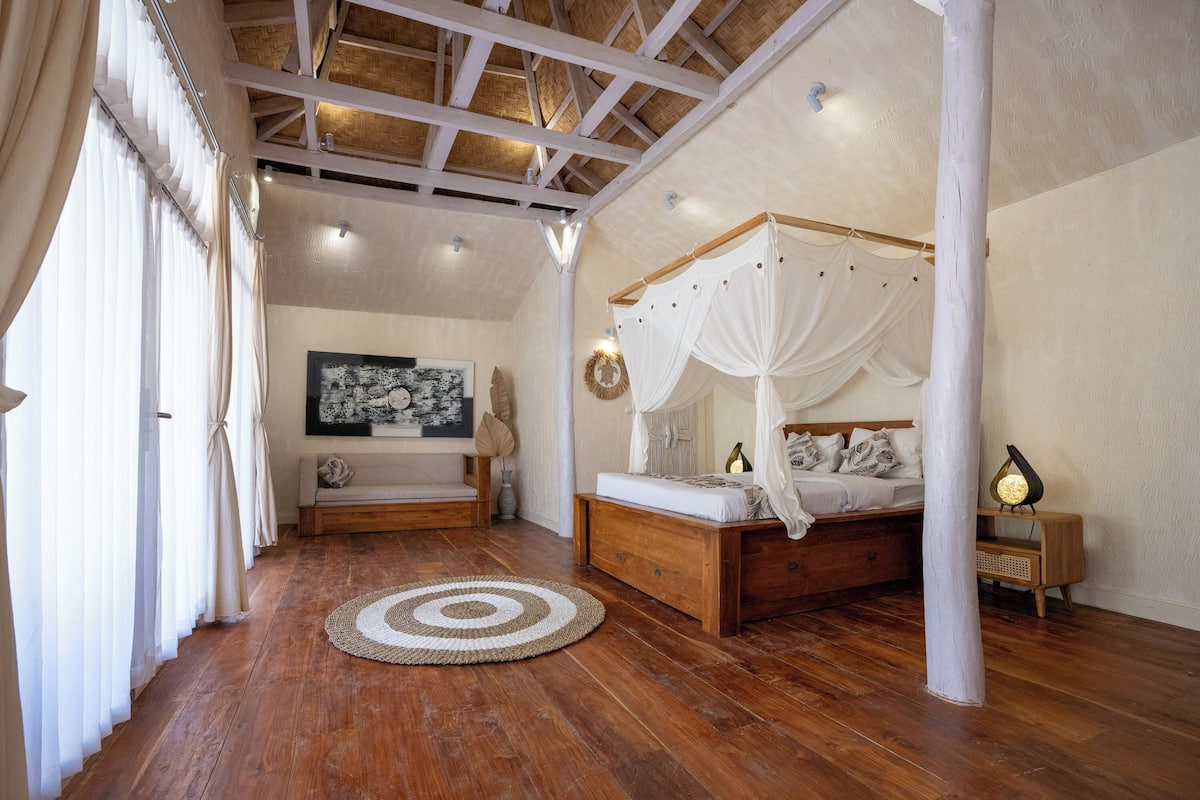 A bedroom with a wooden bed, a round rug, and a large painting on the wall.