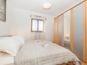 A bedroom with a bed, a window with curtains, a wardrobe, and a bedside lamp. - Villa Marica (Kastela)