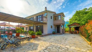 A modern two-story house with a stone patio, outdoor seating, and a pool. - Villa Marica (Kastela)