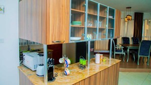 A kitchen with wooden cabinets, a marble countertop, and various kitchen appliances. - Myra Residences Kilimani (Nairobi)
