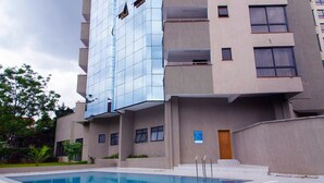 A modern building with a swimming pool, a wooden door, and a blue sign. - Myra Residences Kilimani (Nairobi)