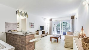 Un salon moderne doté d’une grande fenêtre, d’un coin repas avec un comptoir de cuisine et d’un espace détente confortable avec un canapé et une table basse.