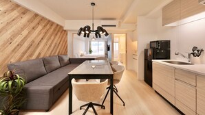 Une cuisine moderne avec un coin repas, un mur d’accent en bois et une vue sur le salon.