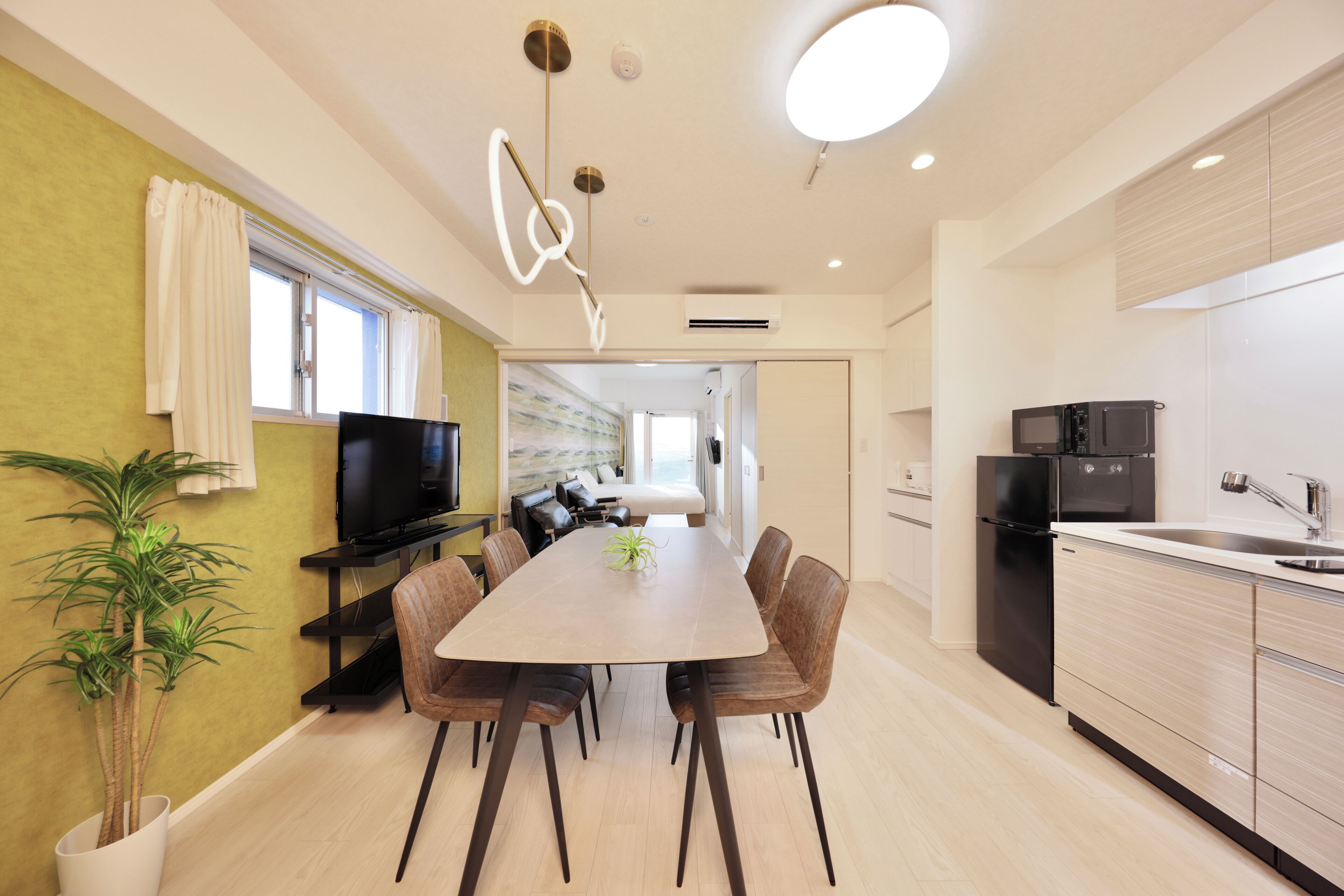 Una cocina moderna con comedor, televisor de pantalla plana y una planta en maceta.