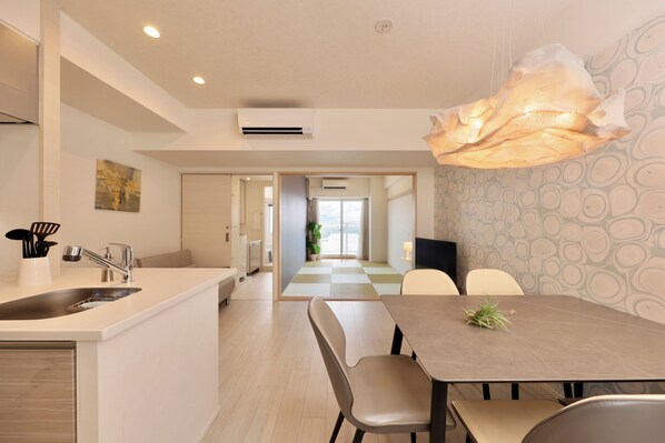 A modern kitchen with a sink, faucet, and countertop. There is a dining area with a table and chairs. - CrystalExe Nannkishirahama1 (Shirahama)
