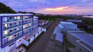 Un hôtel moderne à plusieurs étages, doté de balcons, d’un parking et offrant une vue sur le paysage environnant.