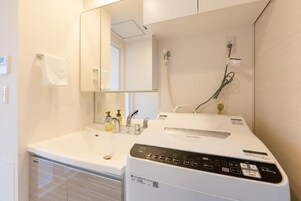 Un baño moderno con un lavamanos blanco, espejo y un secador de pelo en la encimera.