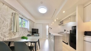 Une cuisine moderne avec un îlot central, un coin repas avec des chaises et un téléviseur en arrière-plan.