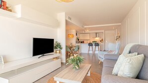 Un soggiorno moderno con una televisione a schermo piatto, un tavolino in legno, un divano grigio e una zona pranzo sullo sfondo.