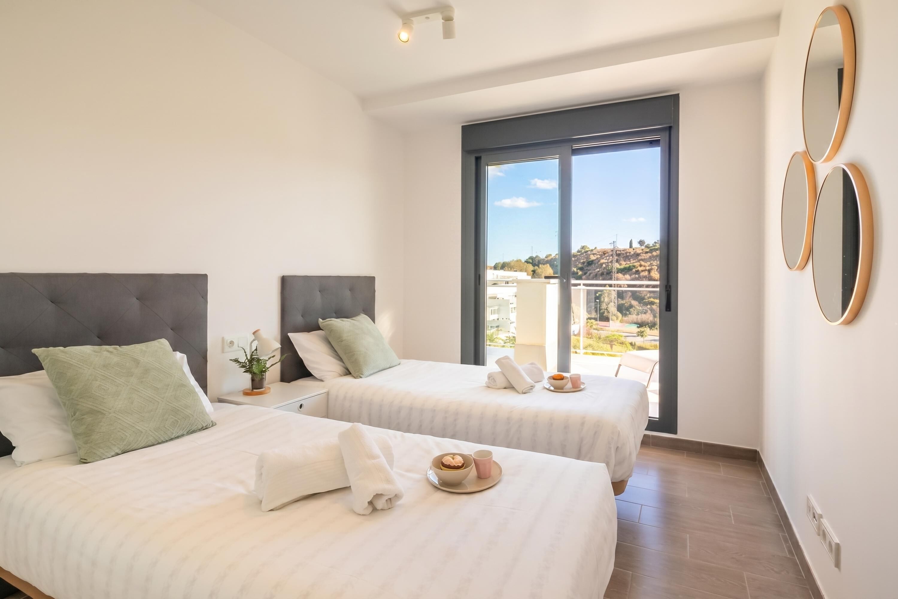 Ein Hotelzimmer mit zwei Betten, einem großen Fenster und einem Balkon.