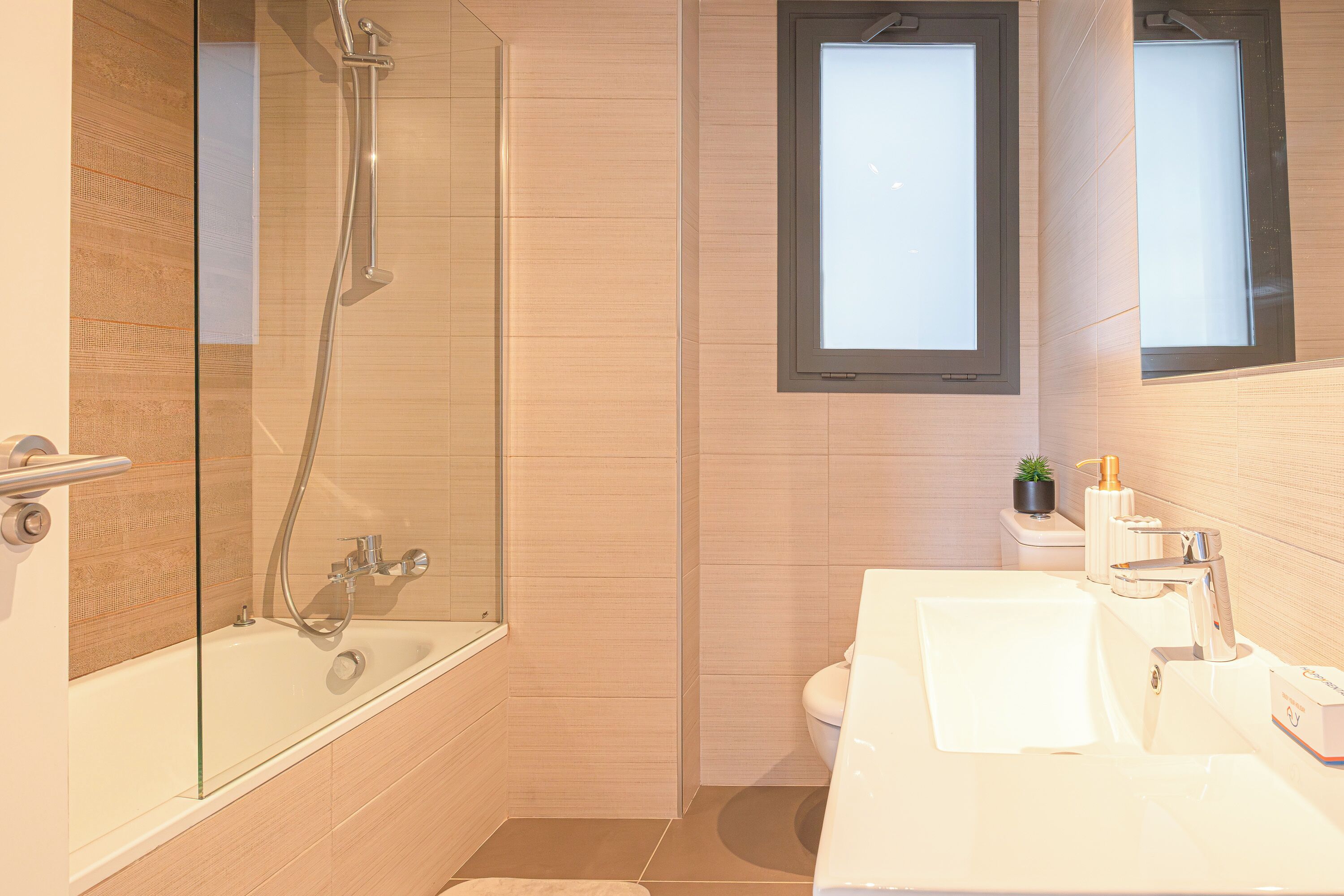 Une salle de bain moderne avec une douche à parois de verre, un lavabo blanc et des toilettes.