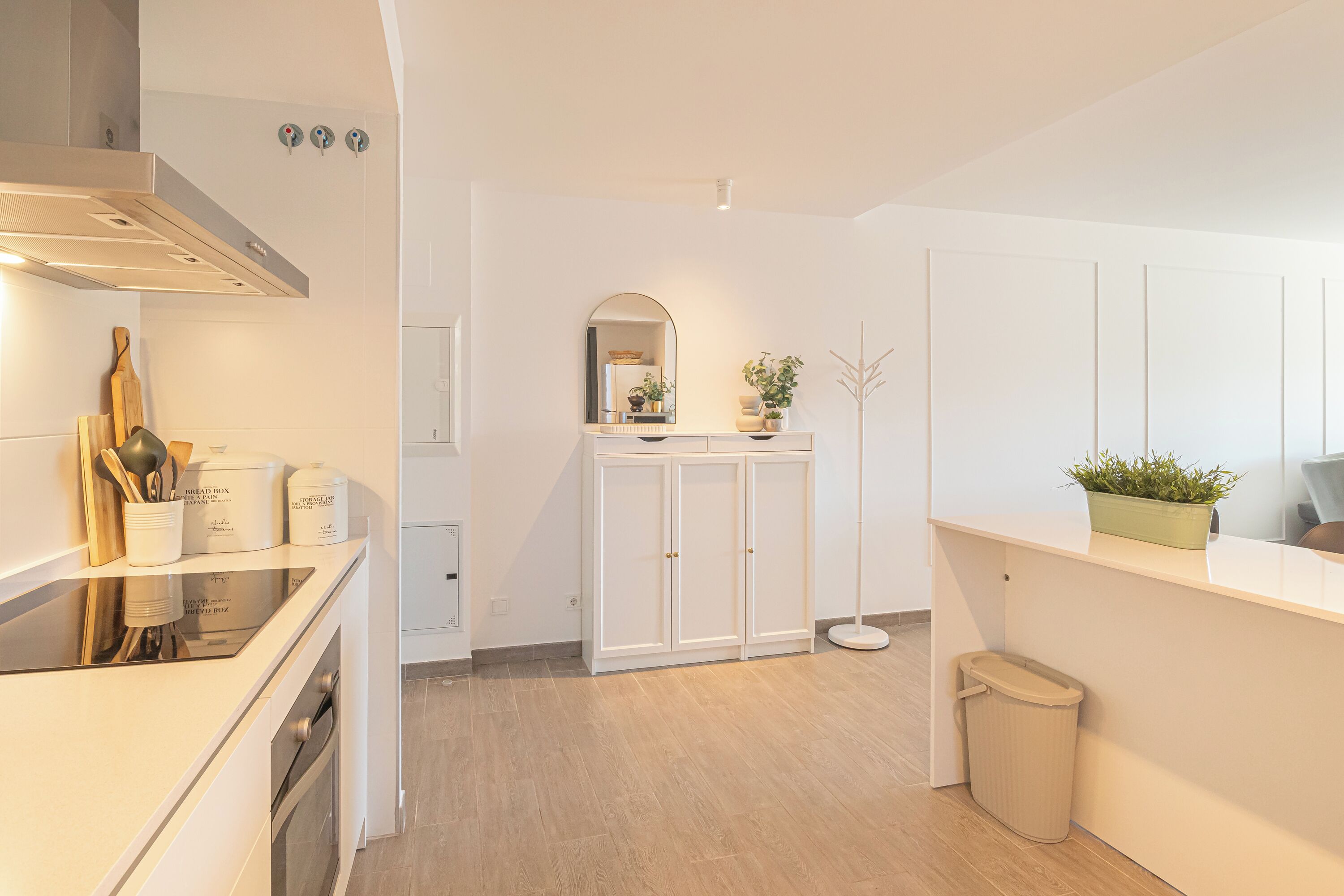 Una cocina moderna con armarios blancos, horno empotrado y encimera con utensilios de cocina.