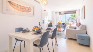 A modern dining area with a white table, dark chairs, and a large painting on the wall. - Sunset Boutique Resina Golf (Estepona)