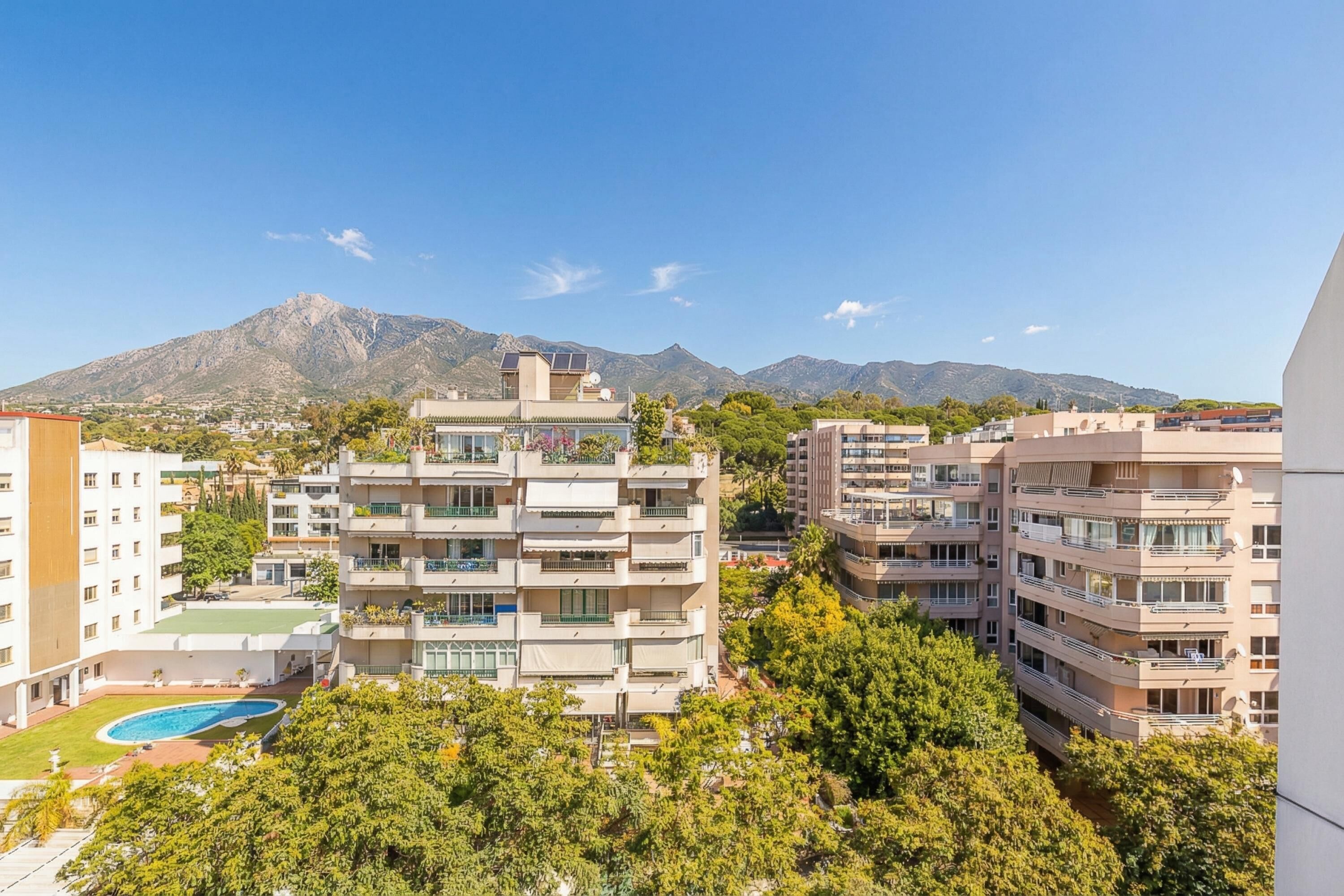 Un hôtel à plusieurs étages doté de balcons, d’une piscine et offrant une vue sur la montagne.