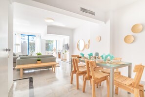 A modern living room with a glass dining table, wooden chairs, a sofa, and a bench. - Marbella House (Marbella)