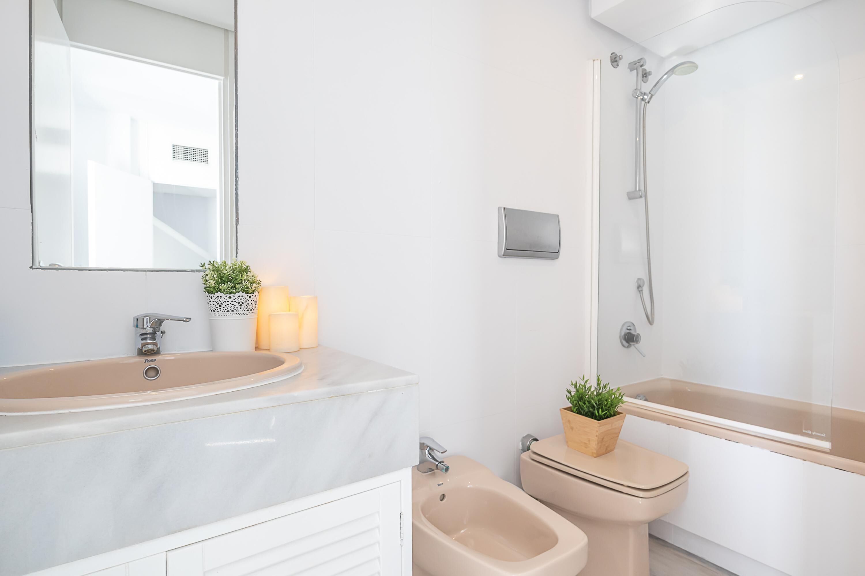 Een moderne badkamer met een marmeren wastafel, een hygiëneschuimer, een toilet en een bad.