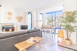 A modern living room with a grey sofa, a wooden table, and a TV. - Marbella House (Marbella)