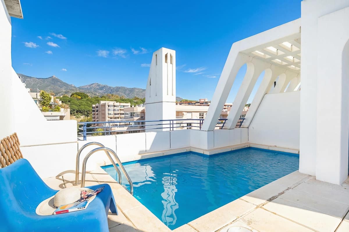 A rooftop pool with a clear view of mountains and a tower in the background.