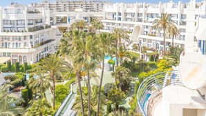 Een modern hotel met meerdere verdiepingen, een zwembadgedeelte en weelderige begroeiing.