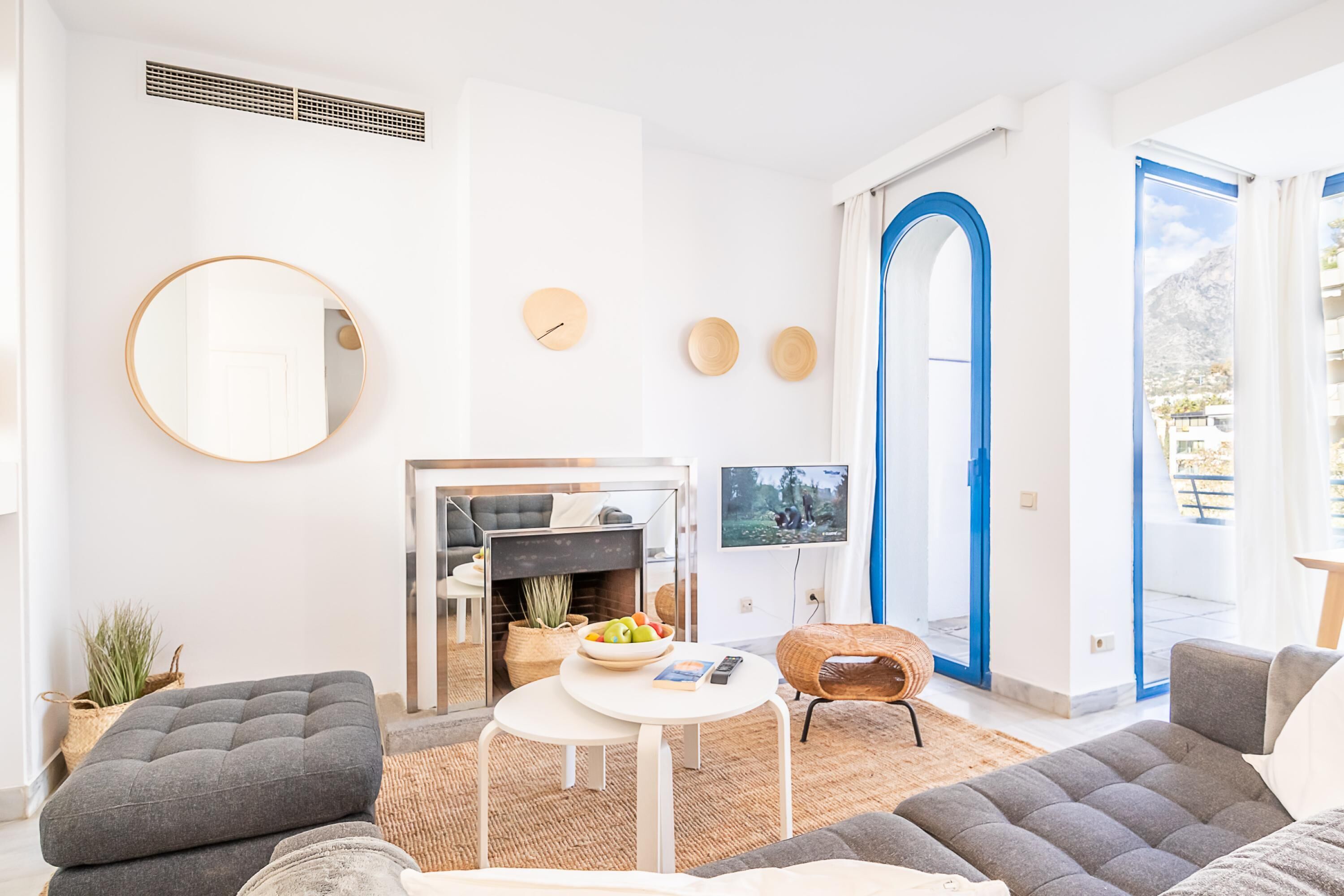 A modern living room with a fireplace, a round mirror, and a television.