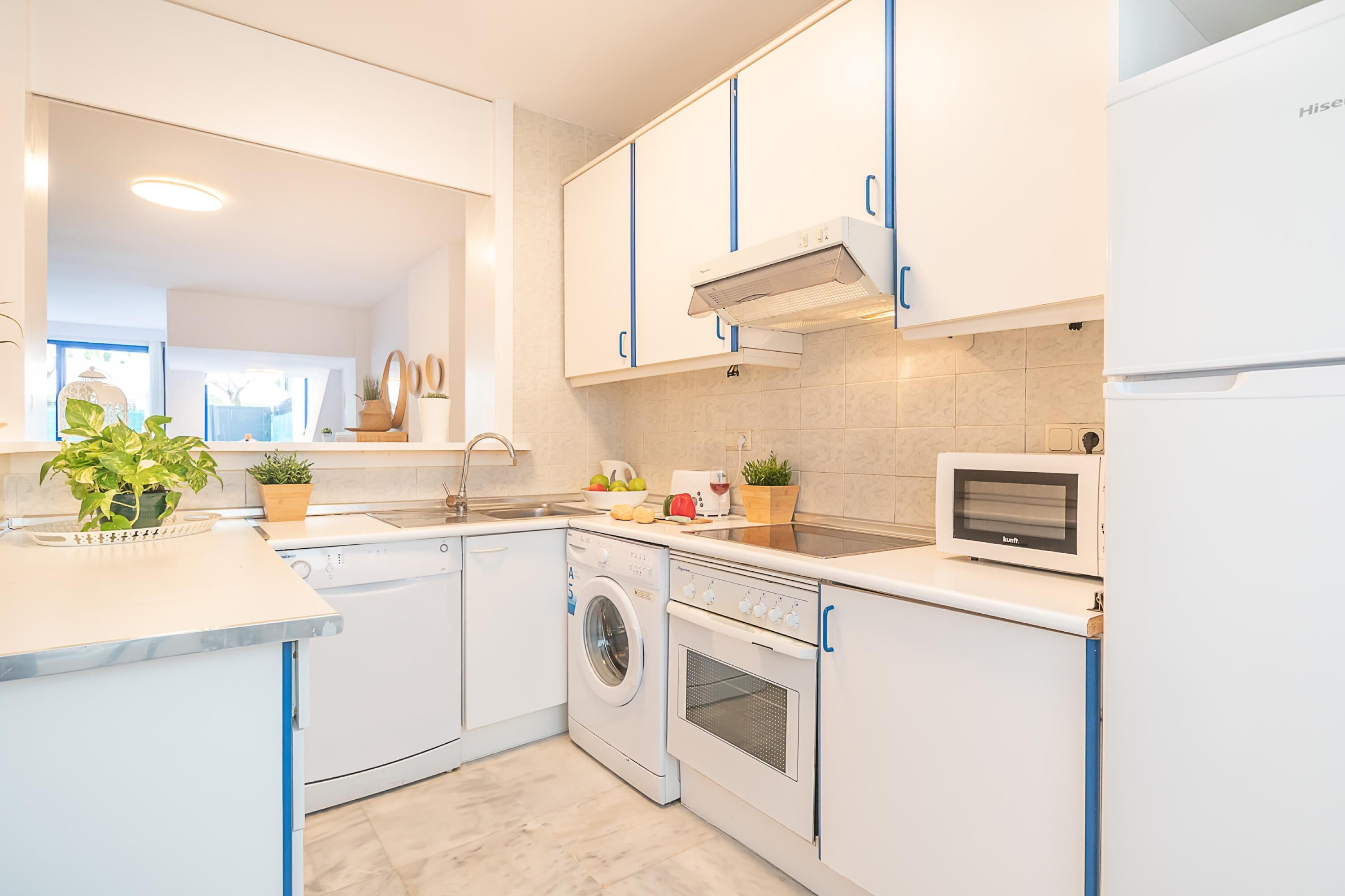 Eine moderne Küche mit weißen Schränken, einem Einbauofen, einer Mikrowelle und einer Waschmaschine.