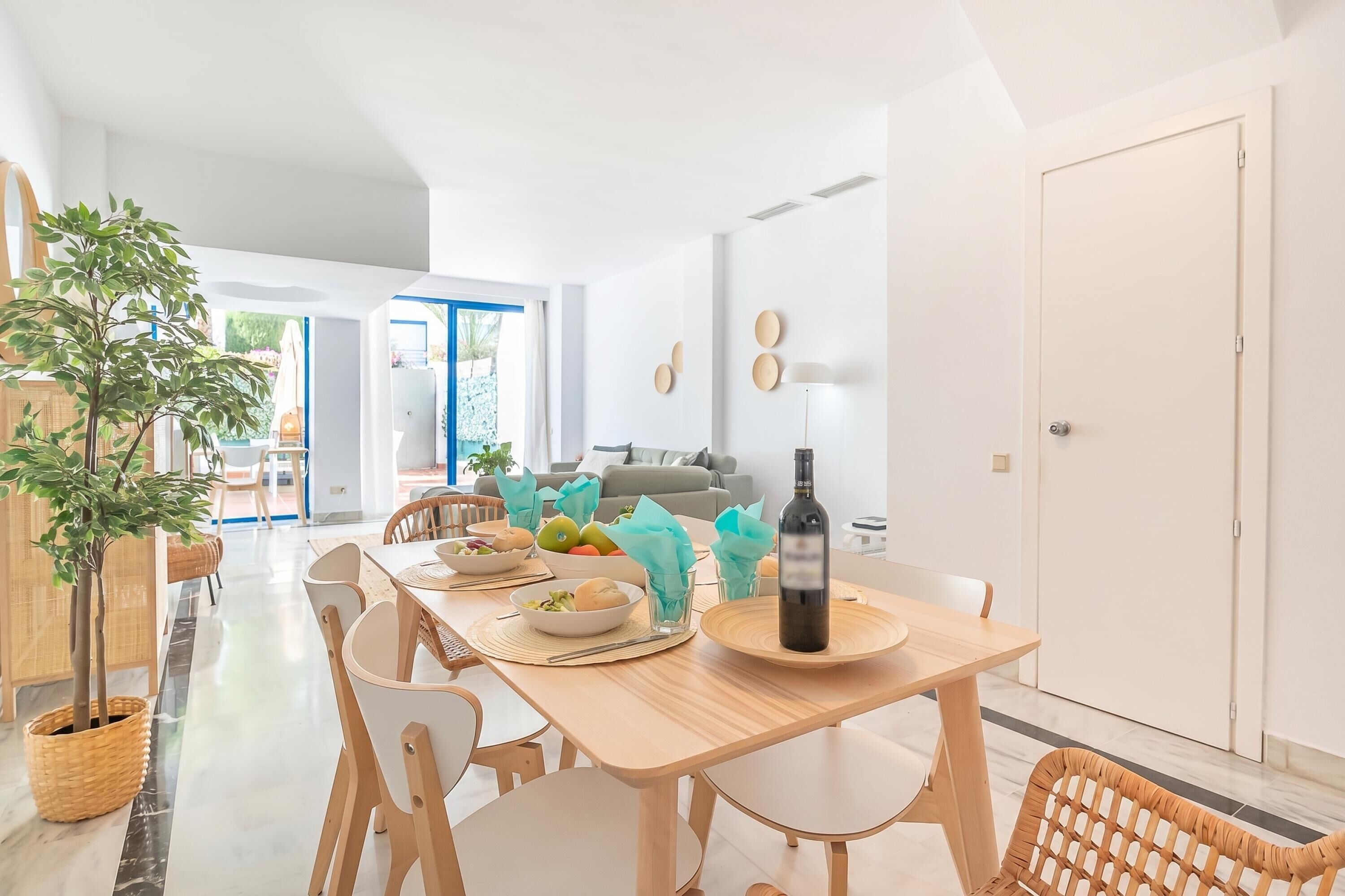 A modern dining area with a wooden table, chairs, a bottle of wine, and a bowl of salad.