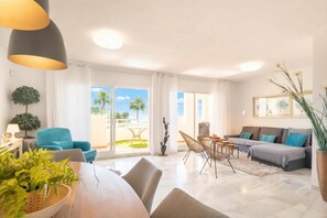 A spacious living area with a dining table, sofas, and a balcony with a view of palm trees. - Calahonda Elegance With Pool And Sea View (Mijas)