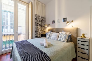 A hotel room with a bed, a nightstand, a lamp, a window with curtains, and a balcony view. - Malaga Center Old Town (Málaga)