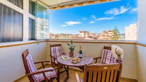 Ein Balkon mit Tisch, Stühlen, einem Blumentopf und einer Champagnerflasche.