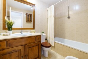A bathroom with a wooden vanity, a white sink, a toilet, a bathtub, and a shower curtain. - La Paloma With Pool (Fuengirola)