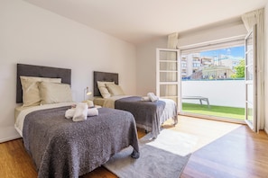 Ein Hotelzimmer mit zwei Betten, einer großen Schiebetür zum Balkon und Blick auf Gebäude.
