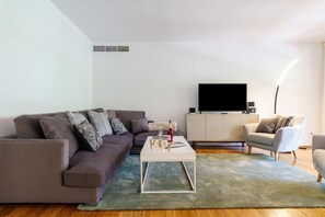 Un salon moderne avec un canapé, une table basse, un téléviseur et une lampe.
