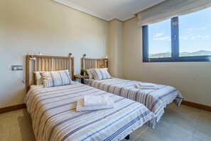 A room with two beds, a window with a view, and a bedside table with a lamp. - Sunset Seaview Corner With Pool (Estepona)