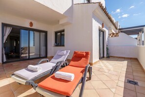 A rooftop terrace with two sun loungers, one with a white towel and the other with an orange cushion. - Sunset Seaview Corner With Pool (Estepona)