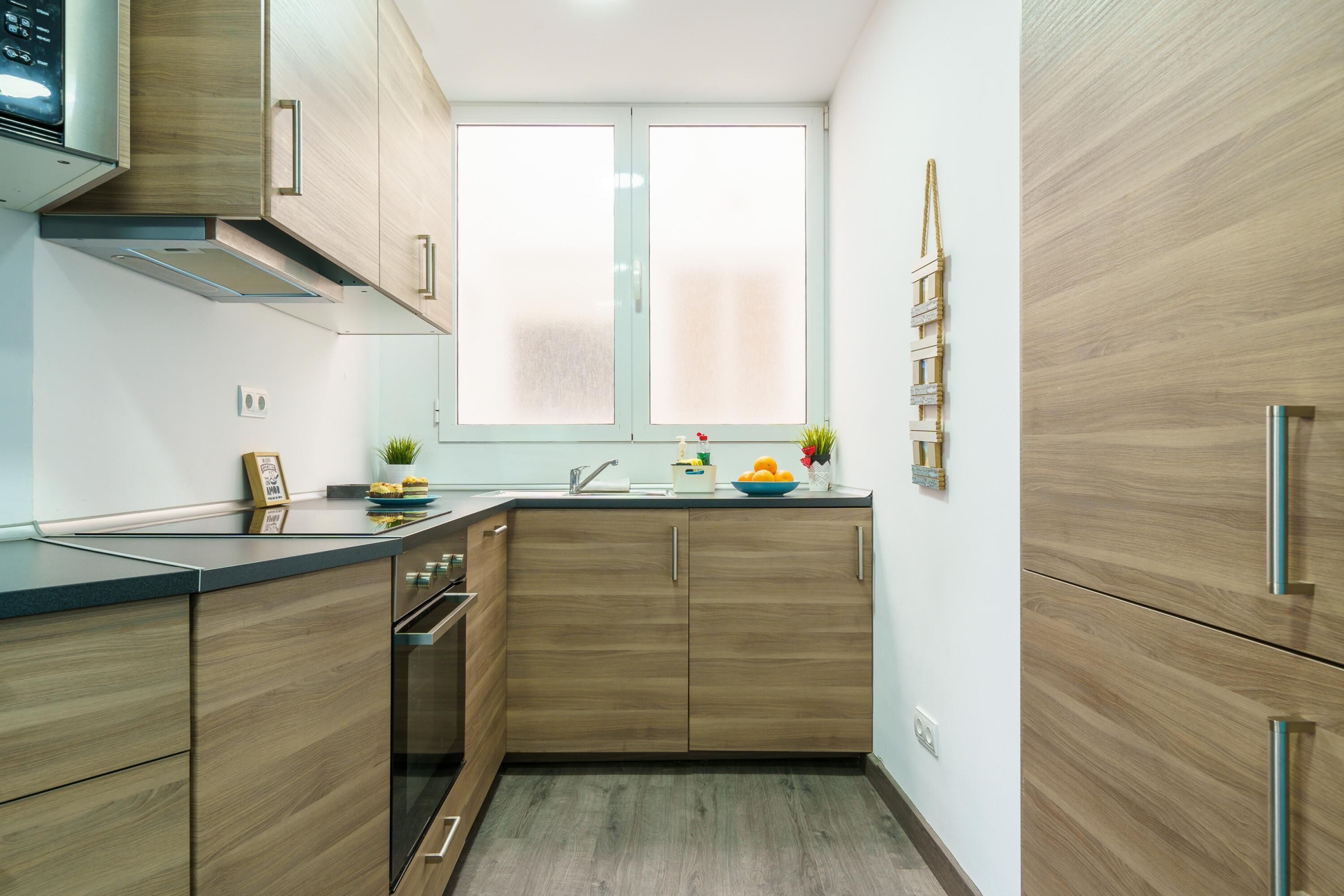 Une cuisine moderne avec des meubles en bois, un four encastré et une fenêtre.