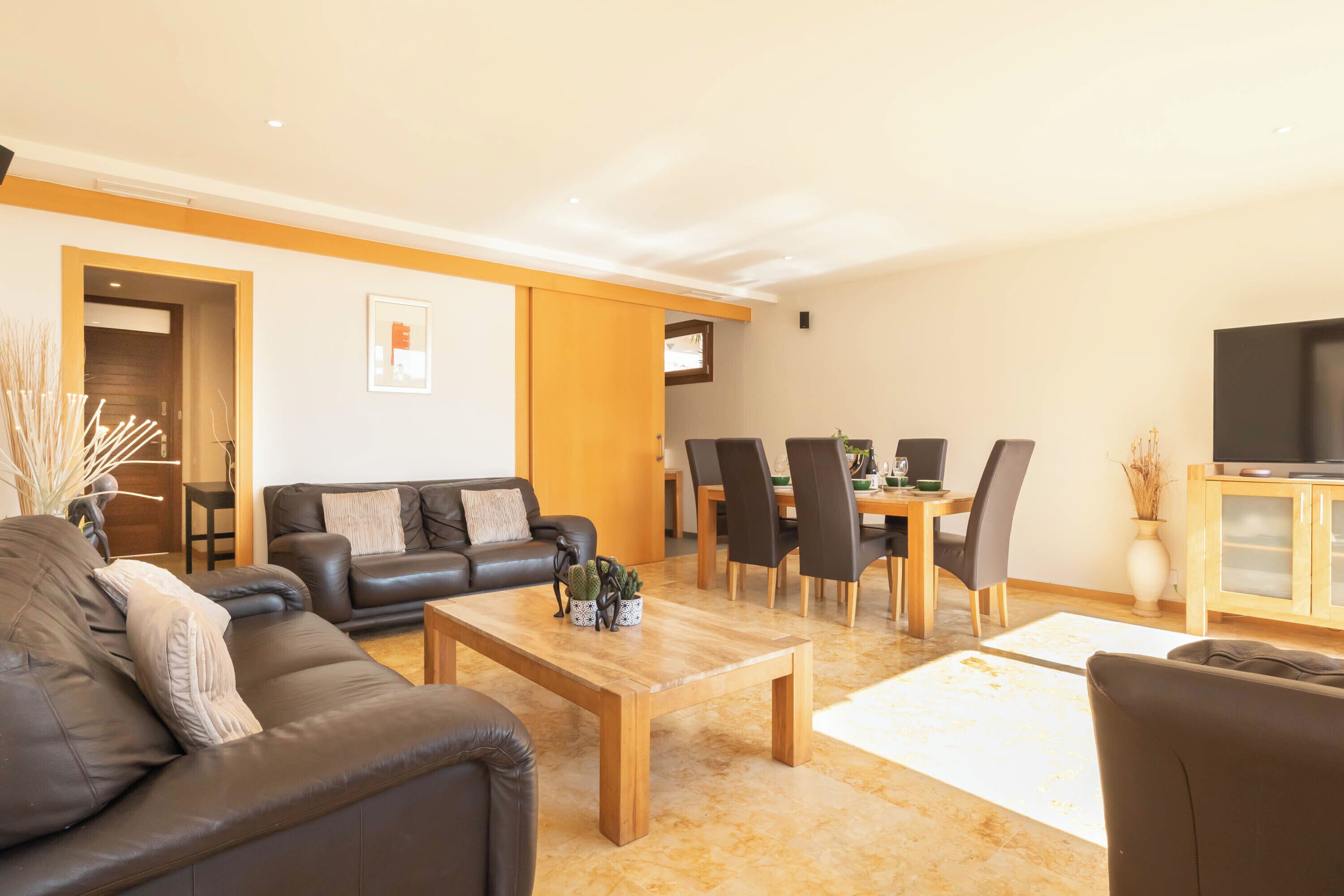 A modern living room with a sofa, coffee table, and dining area.