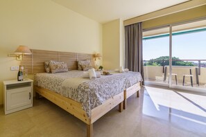A bedroom with a wooden bed, a nightstand with a lamp, a balcony with a view.