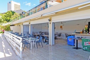 An outdoor café with tables and chairs, a counter with a beverage dispenser, and a view of a building in the background. - Marbella Este Next Marriott and Nikki B (Marbella)