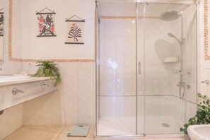 Une salle de bain avec une douche à parois de verre, un lavabo et des éléments décoratifs sur les murs.