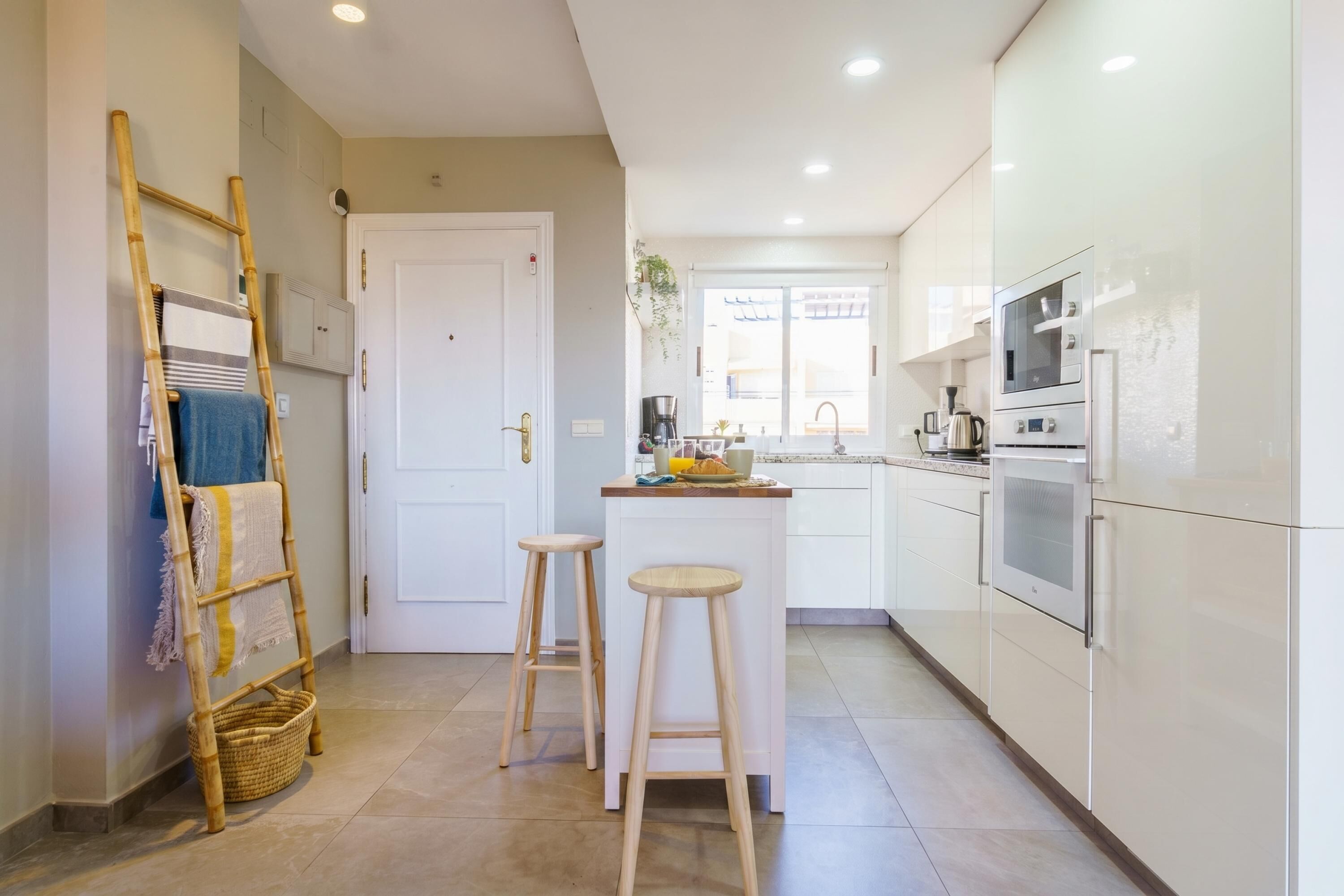A kitchen with white cabinets, a wooden ladder, two stools, and a small island.