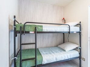 Ein Etagenbett mit einer Leiter, Bettwäsche in Grün und Weiß, und eine rote Lampe an der Wand.