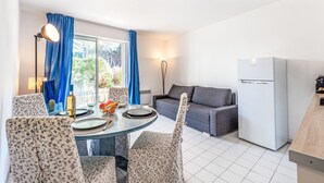 Eine moderne Küche mit Essbereich, einem grauen Sofa und einem weißen Kühlschrank.