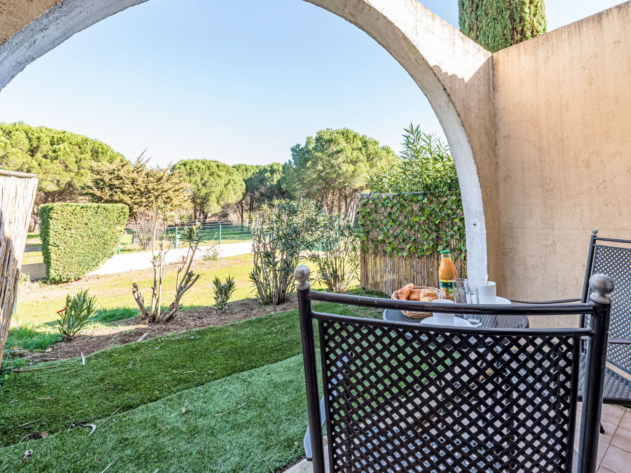 A patio area with a table and chairs, a basket of bread, and a bottle of drink.