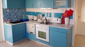 Une cuisine avec des meubles bleus, un plan de travail blanc, une cuisinière et une machine à café.
