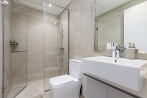 Ein modernes Badezimmer mit einer Duschkabine, einem weißen Waschbecken und einer Toilette.
