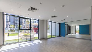 Une pièce spacieuse avec de grandes fenêtres, un parquet clair et un mur d’accent bleu.