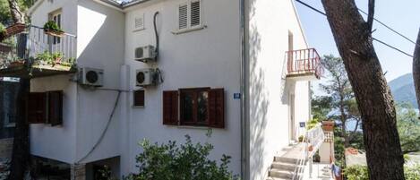 A two-story building with a balcony, air conditioning units, and a staircase leading to the upper floor.