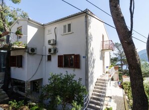 A two-story building with a balcony, air conditioning units, and a staircase leading to the upper floor. - Guest House Sobra 38 (Mljet)